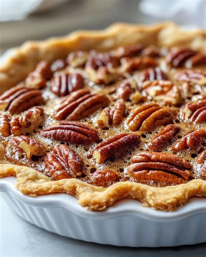 Ingredients for Maple Pecan Pie. Syrup being poured into pie crust.